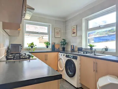 a kitchen with a washing machine and a sink at Bright 4BR Home Near Anfield & Free Parking in Liverpool