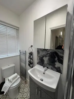 a bathroom with a sink and a toilet and a mirror at Louise Suite in Southport