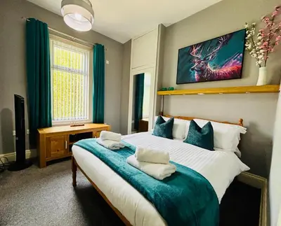 a bedroom with a large bed with a blue blanket at Michaels Suite in Southport