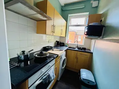 a small kitchen with a stove and a sink at Michaels Suite in Southport