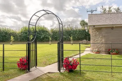 an open gate with red flowers in a field at Ribblesdale Cottage in Acres of Countryside in Chatburn