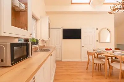 a kitchen with white cabinets and a table with chairs at Ribblesdale Cottage in Acres of Countryside in Chatburn
