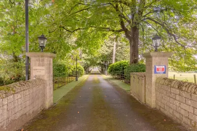 a street with two entrances to a park with trees at Ribblesdale Cottage in Acres of Countryside in Chatburn