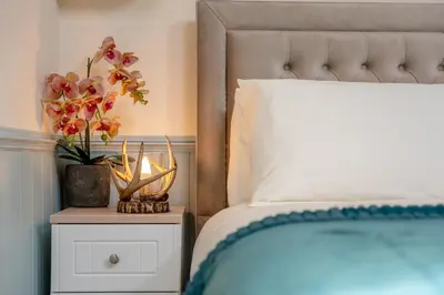 a bed with a vase of flowers on a night stand at Ribblesdale Cottage in Acres of Countryside in Chatburn