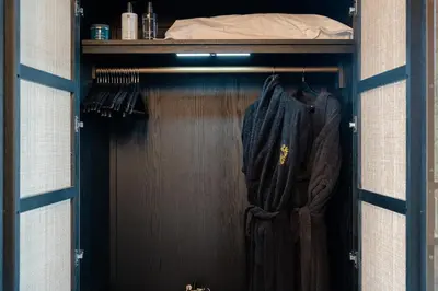 a closet with a wooden door and clothes hanging at Brierley Club Hideaway Chic 7 Star Retreat in Rishton
