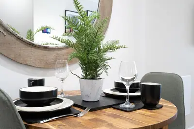 a table with glasses and a potted plant on it at Luxury Waterfront Apartment - Liverpool City Centre - Sleeps 4 in Liverpool