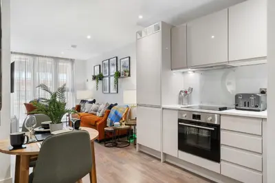 a kitchen with white cabinets and a table and a dining room at Luxury Waterfront Apartment - Liverpool City Centre - Sleeps 4 in Liverpool