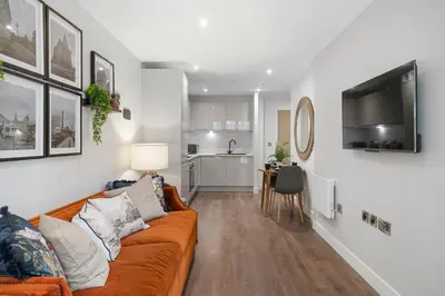 a living room with a couch and a kitchen at Luxury Waterfront Apartment - Liverpool City Centre - Sleeps 4 in Liverpool