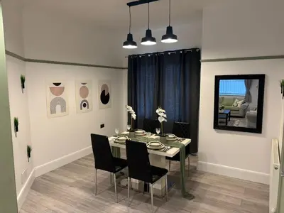 a dining room with a table and black chairs at The Bohe Home in Wallasey