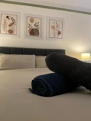 a towel on a bed with pictures on the wall at The Bohe Home in Wallasey