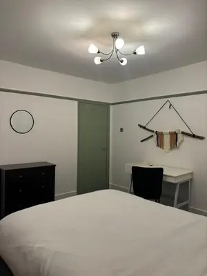 a bedroom with a bed and a desk and a chandelier at The Bohe Home in Wallasey