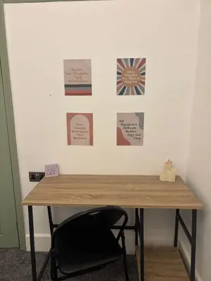 a desk with a chair in front of a wall with posters at The Bohe Home in Wallasey