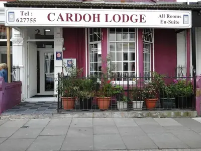a garden lodge with potted plants in front of a building at Cardoh Lodge in Blackpool