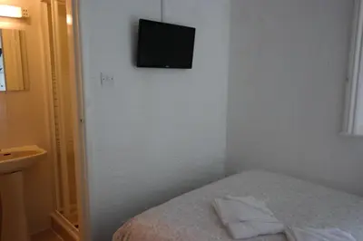 a bedroom with a bed with a television on the wall at Cardoh Lodge in Blackpool