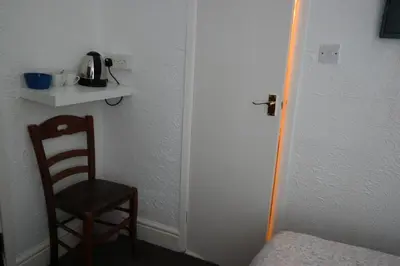 a room with a chair and a table and a door at Cardoh Lodge in Blackpool