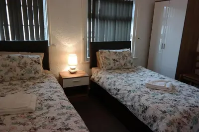 a bedroom with two beds and a lamp on a table at Cardoh Lodge in Blackpool