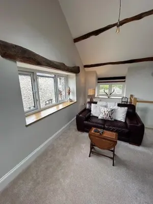 a living room with a couch and two windows at The Tractor House in Great Urswick