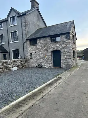 an old stone building with a door on a street at The Tractor House in Great Urswick