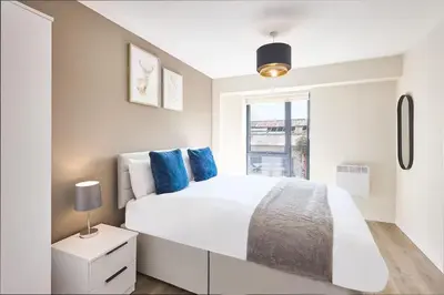 a white bedroom with a large bed with blue pillows at 2 Bed - Sleeps 6 - Parking - City Centre in Liverpool
