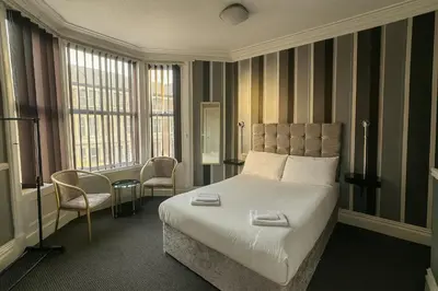 a hotel room with a bed and two chairs at Rest and Welcome B&B, Blackpool in Blackpool