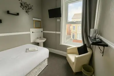 a bedroom with a bed and a chair and a window at Rest and Welcome B&B, Blackpool in Blackpool
