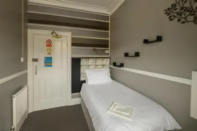 a small bedroom with a white bed and a door at Rest and Welcome B&B, Blackpool in Blackpool