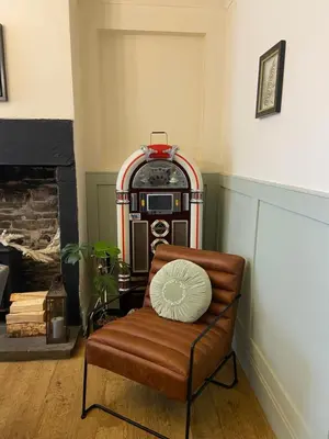 a chair with a pillow in a room with a stove at Old Store Cottage, Up Holland in Upholland