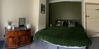 a bedroom with a green bed and a wooden dresser at Old Store Cottage, Up Holland in Upholland