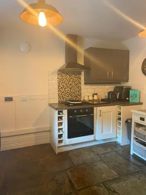 a kitchen with a stove top oven in a room at Old Store Cottage, Up Holland in Upholland