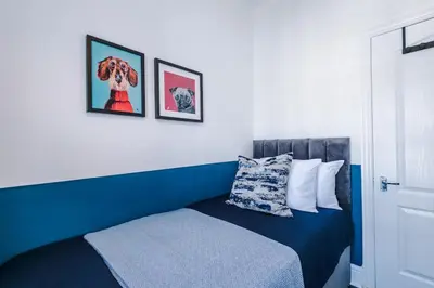 a bedroom with a blue bed with two pictures on the wall at Skipton House Business Travel Accommodation Parking Liverpool in Liverpool