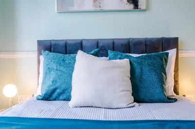 a bed with blue and white pillows on it at Skipton House Business Travel Accommodation Parking Liverpool in Liverpool