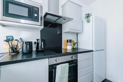 a kitchen with white cabinets and a black counter top at Skipton House Business Travel Accommodation Parking Liverpool in Liverpool
