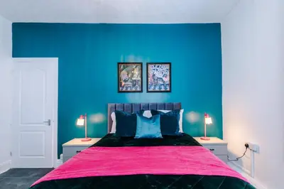 a blue bedroom with a large bed with a pink blanket at Skipton House Business Travel Accommodation Parking Liverpool in Liverpool