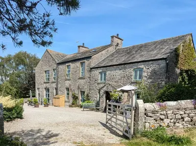 an old stone house with a gate in front of it at The Old Farmhouse at Brackenthwaite Farm in Carnforth
