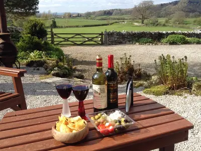 a picnic table with two bottles of wine and a basket of food at The Old Farmhouse at Brackenthwaite Farm in Carnforth
