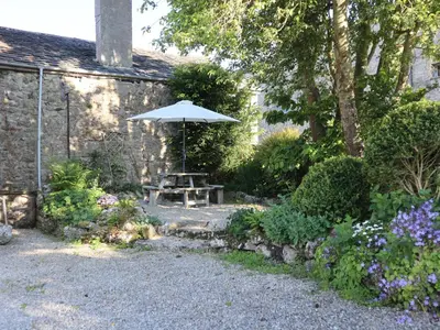 a picnic table with an umbrella in a garden at The Old Farmhouse at Brackenthwaite Farm in Carnforth