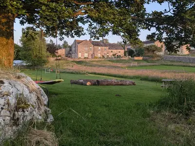 a tree log laying on the grass in a field at The Old Farmhouse at Brackenthwaite Farm in Carnforth