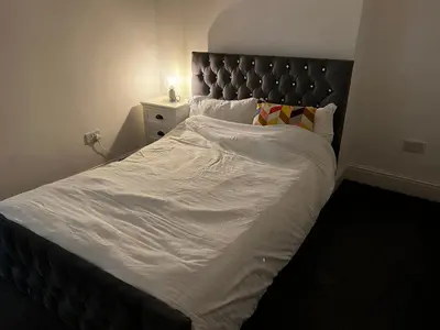 a large bed with white sheets and a black headboard at Crosby Marina Apartment in Waterloo