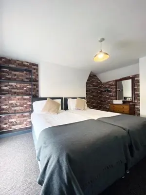 a bedroom with a large bed and a brick wall at The Docklands XL by Serviced Living Liverpool in Liverpool