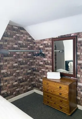 a bedroom with a mirror on a brick wall at The Docklands XL by Serviced Living Liverpool in Liverpool