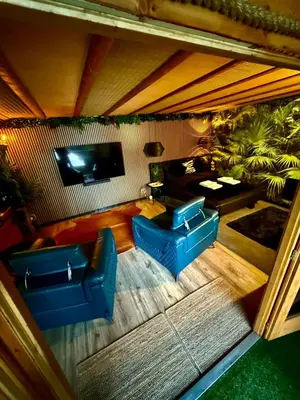 a living room with two blue chairs and a television at Woodland Escapes Glamping - Lake View