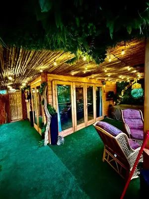 a living room with a couch and chairs on a green carpet at Woodland Escapes Glamping - Lake View
