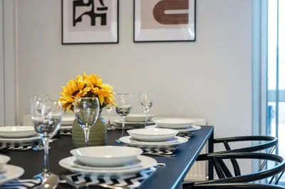 a black table with plates and glasses and a vase with yellow flowers at Balfour House - Air Host & Stay - Sleeps 8, free parking in Litherland