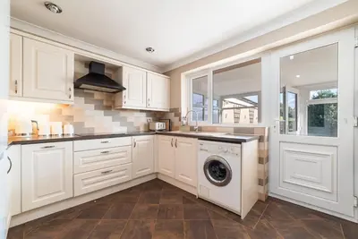 a kitchen with white cabinets and a washing machine at 2 Bed Modern Bungalow in Darwen, Garden & Parking in Darwen