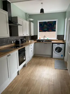 a kitchen with white cabinets and a washer and dryer at ML Short Stays - 3 Bedroom House Near BAE in Barrow in Furness