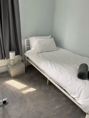 a bedroom with a bed with white sheets at ML Short Stays - 3 Bedroom House Near BAE in Barrow in Furness