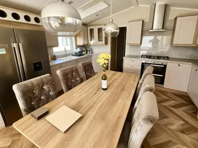 a kitchen with a wooden table with chairs and a bottle of wine at Ocean Edge Leisure Park - 21286 in Morecambe