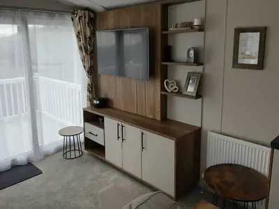 a living room with a television and a stool at Lakeland Leisure Park - 20349 in Grange Over Sands