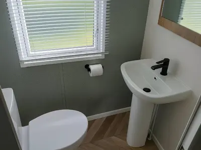 a bathroom with a sink and a toilet and a window at Lakeland Leisure Park - 20349 in Grange Over Sands