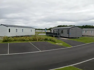 a parking lot with two houses and a tennis court at Lakeland Leisure Park - 20349 in Grange Over Sands